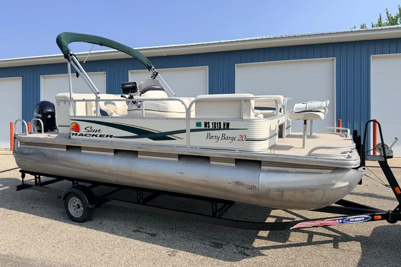 The Image of 2010 Sun Tracker Party Barge 20 Classic pontoon boat on trailer, parked near blue building. - 1