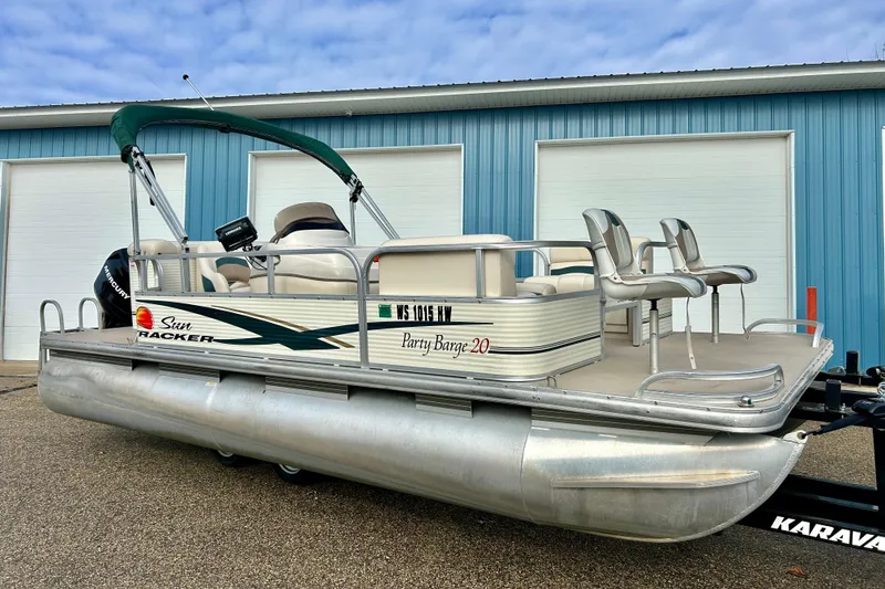 Slide: The Image of 2010 Sun Tracker Party Barge 20 Classic pontoon boat with canopy, parked near blue building. - 4