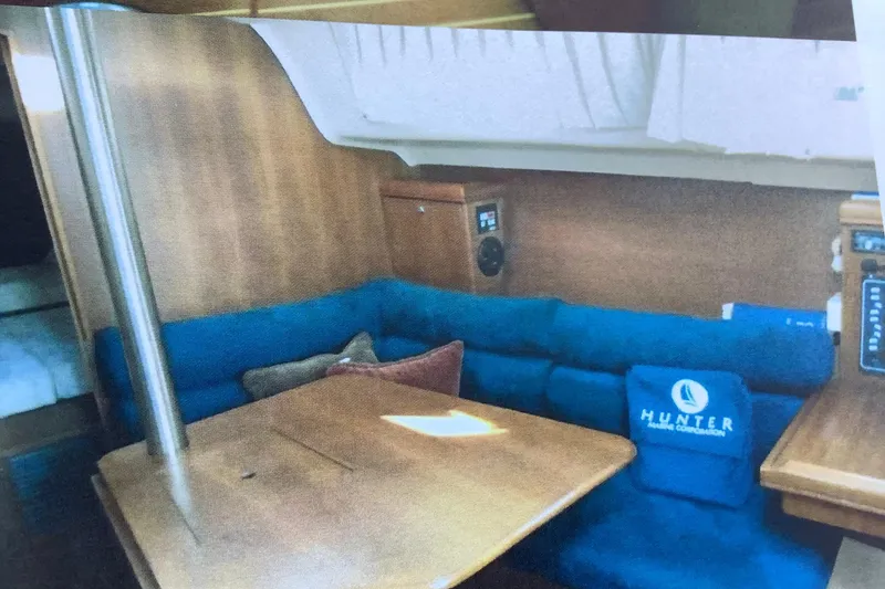 Slide: The Image of Interior of a 2003 Hunter 306 sailboat with blue seating and wooden table. - 11