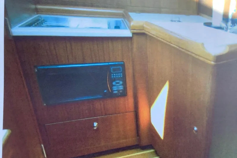 Slide: The Image of 2003 Hunter 306 yacht interior kitchen with microwave and wooden cabinetry. - 12