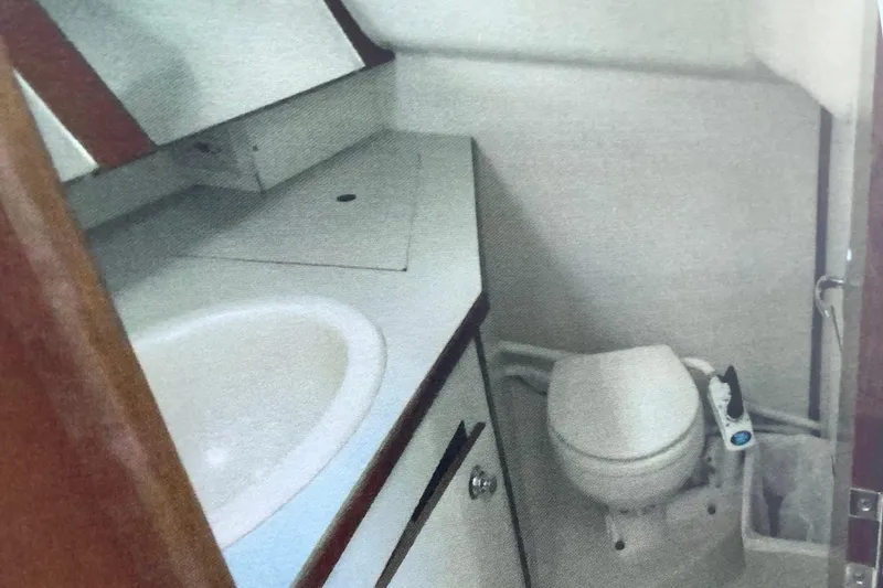 Slide: The Image of Compact bathroom in a 2003 Hunter 306 sailboat, featuring a sink and marine toilet. - 14