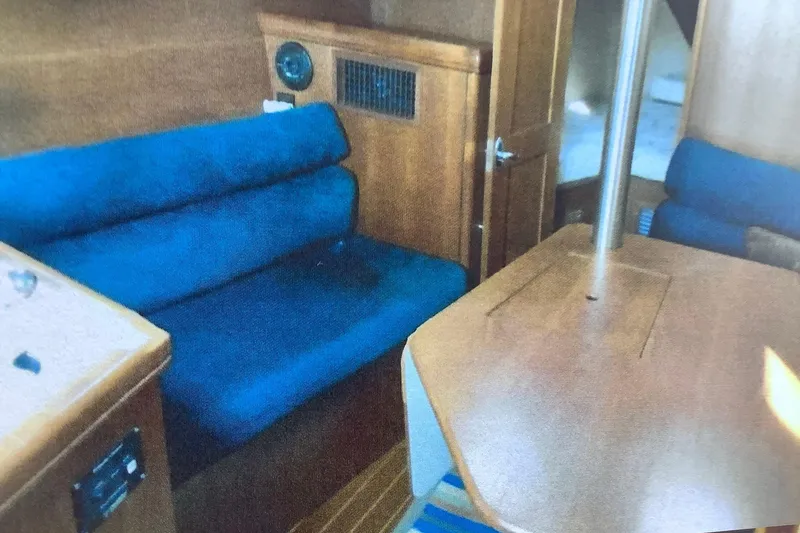 Slide: The Image of Interior of a 2003 Hunter 306 sailboat with blue seating and wooden table. - 13