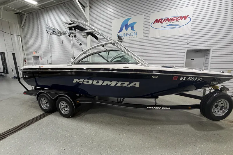 The Image of 2010 Moomba LSV boat in showroom, featuring sleek design and dual-axle trailer. - 1