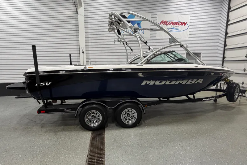 Slide: The Image of 2010 Moomba LSV boat in showroom, featuring sleek design and dual-axle trailer. - 8