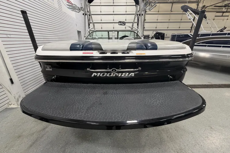 Slide: The Image of 2010 Moomba LSV boat rear view in showroom, featuring swim platform and sleek design. - 5