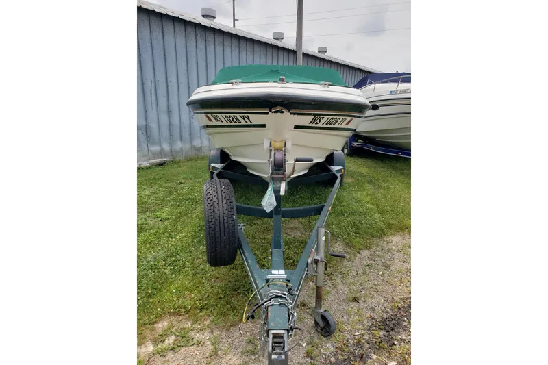 Slide: The Image of 1998 Chaparral 2130 SS boat on trailer, parked beside a metal building. - 2