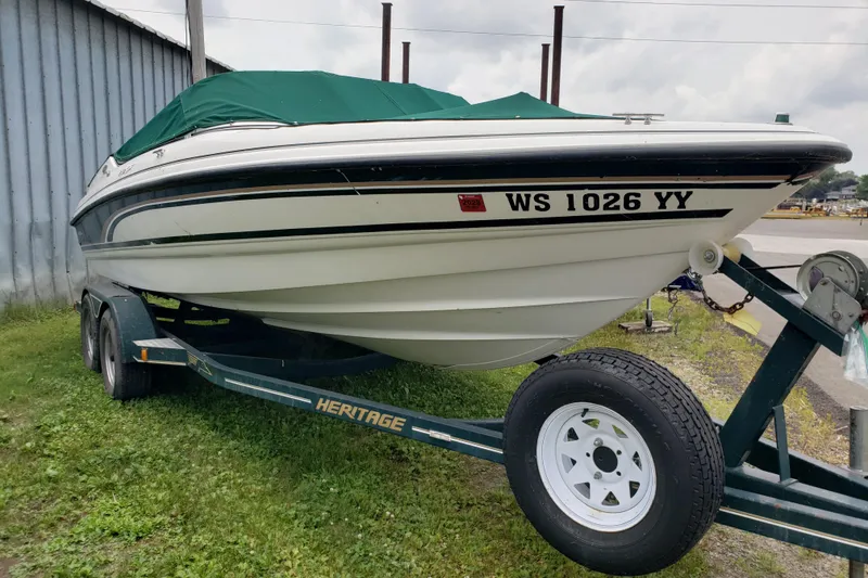 The Image of 1998 Chaparral 2130 SS boat on trailer with green cover, parked outdoors. - 0