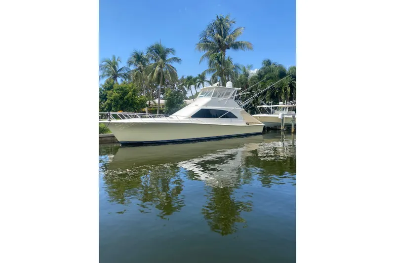 The Image of 1996 Ocean Super Sport yacht docked by palm trees, reflecting on calm water. - 0