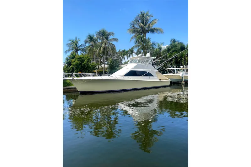 Slide: The Image of 1996 Ocean Super Sport yacht docked by palm trees, reflecting on calm water. - 5