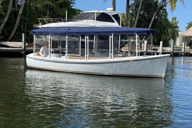 Slide: The Image of 2021 Duffy Bay Island 22 boat on calm water, featuring a blue canopy and clear enclosures. - 7