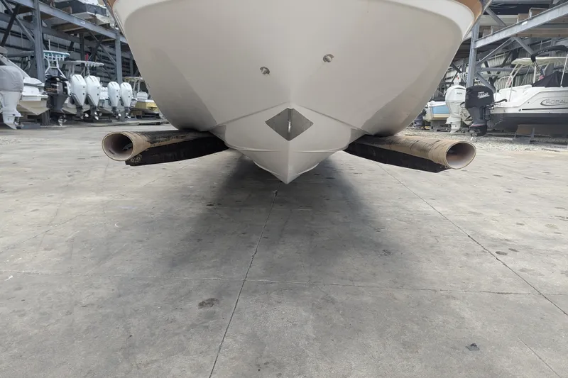 Slide: The Image of 2017 Four Winns HD240 boat on dry dock, viewed from the front, with storage racks nearby. - 6