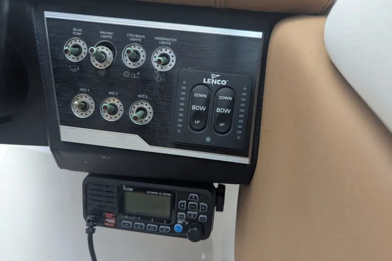 Slide: The Image of Control panel of a 2017 Four Winns HD240 boat with switches and Lenco trim tab controls. - 16