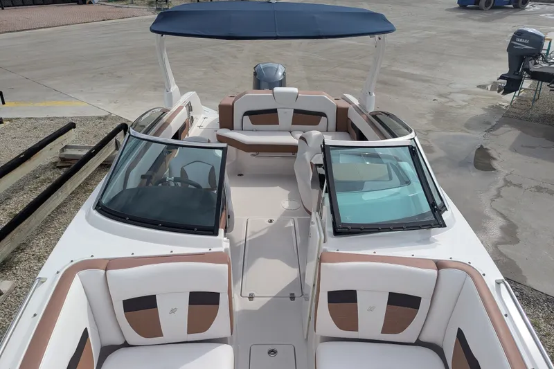 Slide: The Image of 2017 Four Winns HD240 boat with spacious seating and blue canopy, docked on concrete. - 10