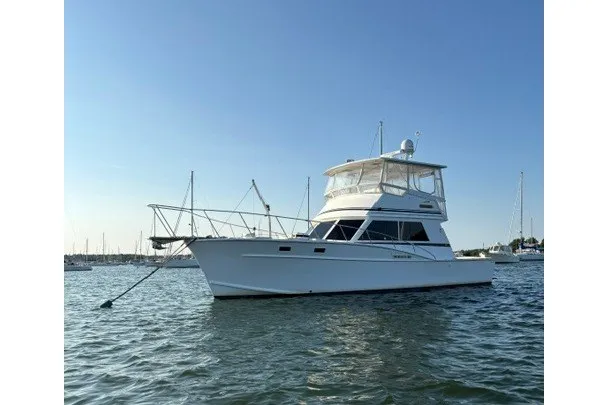 Slide: The Image of 1987 Fortier 40 yacht anchored in a serene marina setting. - 1