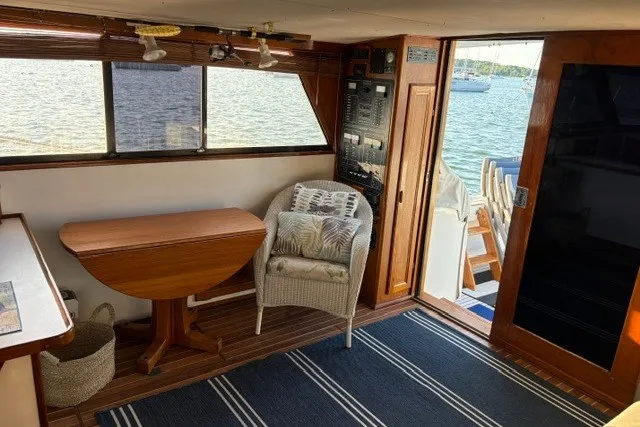 Slide: The Image of Interior of 1987 Fortier 40 boat with wooden table, wicker chair, and scenic water view. - 12