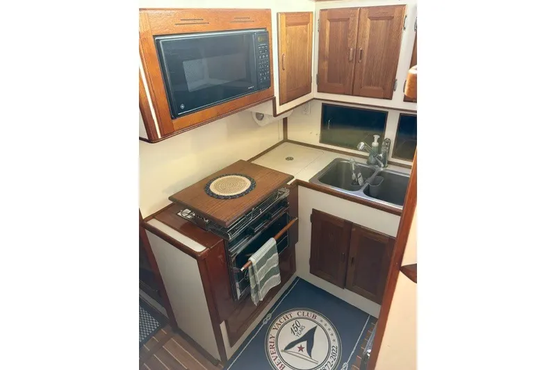 Slide: The Image of Compact kitchen in a 1987 Fortier 40 yacht with wooden cabinets and modern appliances. - 14