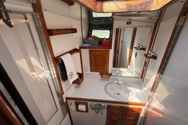 Slide: The Image of 1987 Fortier 40 yacht bathroom with wooden accents, sink, mirror, and storage cabinets. - 17