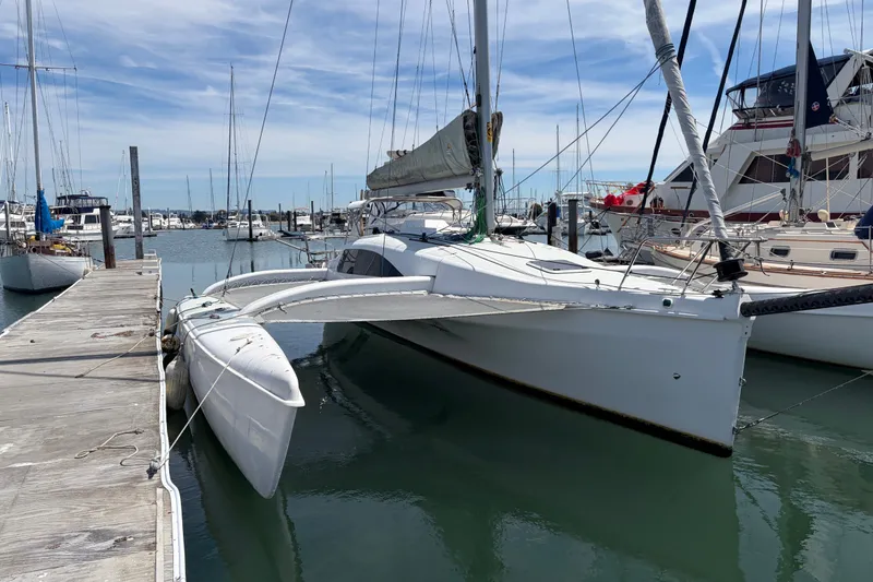 Slide: The Image of 2004 Corsair 36 trimaran docked at a marina, surrounded by other boats. - 17