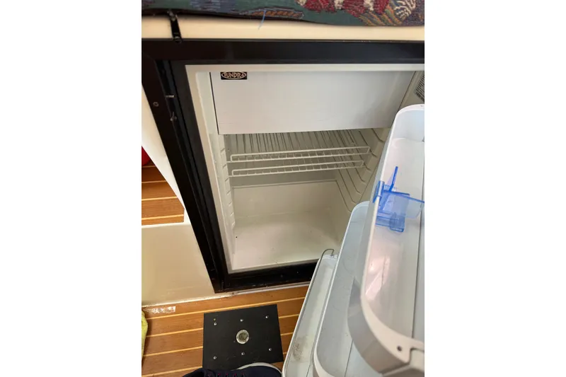 Slide: The Image of Open fridge inside a 2004 Corsair 36 boat, showing empty shelves and door storage. - 6