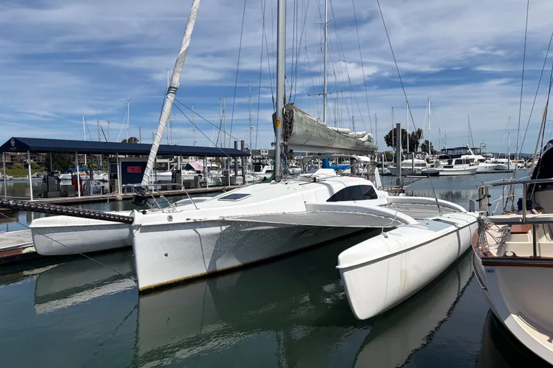 Slide: The Image of 2004 Corsair 36 trimaran docked at a marina under a clear blue sky. - 18