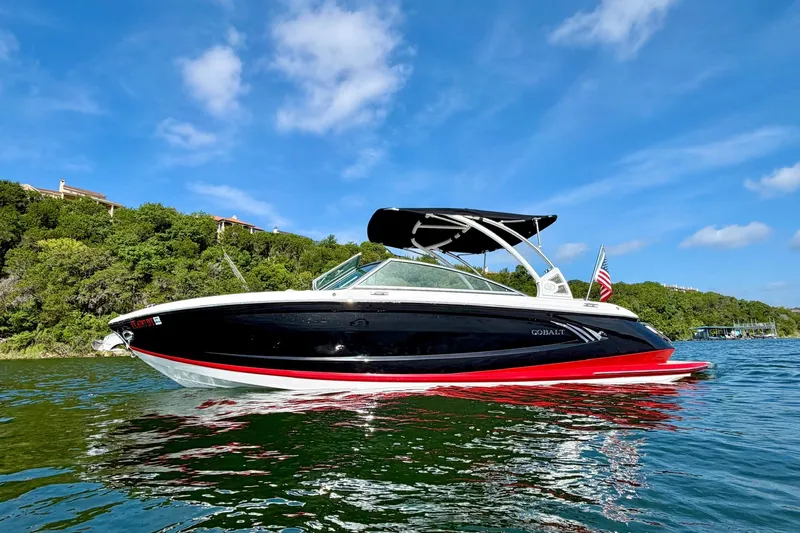 Slide: The Image of 2017 Cobalt A25 boat on water, black and red design, clear sky background. - 5
