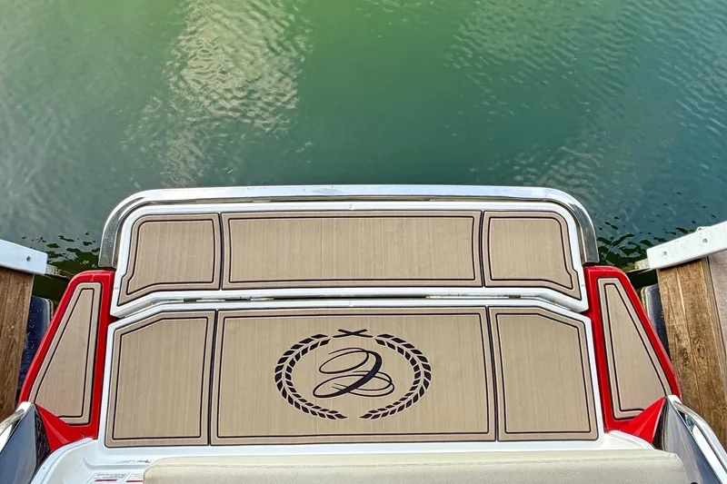 Slide: The Image of 2017 Cobalt A25 boat swim platform with custom logo, docked on calm green water. - 32