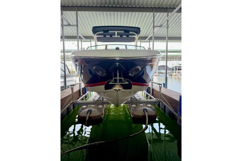 Slide: The Image of Front view of a 2017 Cobalt A25 boat docked in a covered marina. - 25