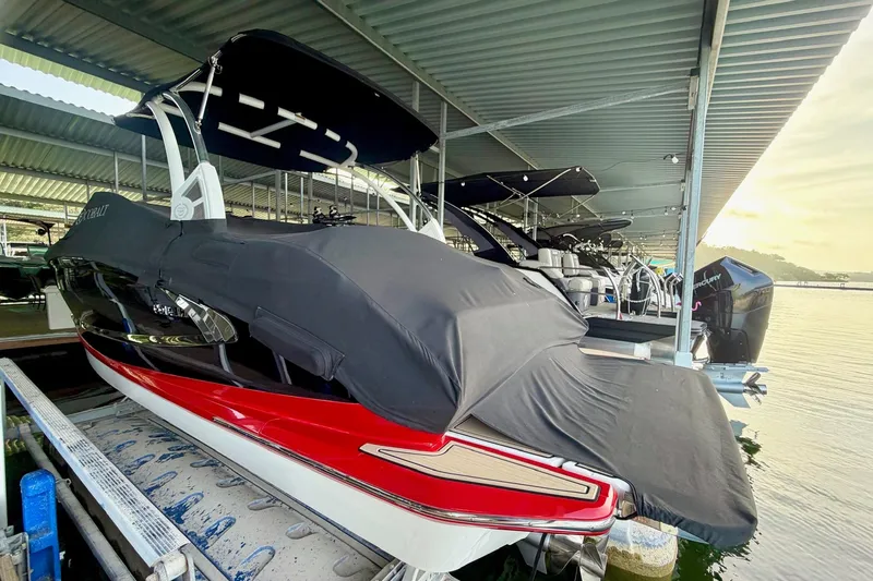 Slide: The Image of 2017 Cobalt A25 boat with cover, docked under a metal roof at a marina. - 28