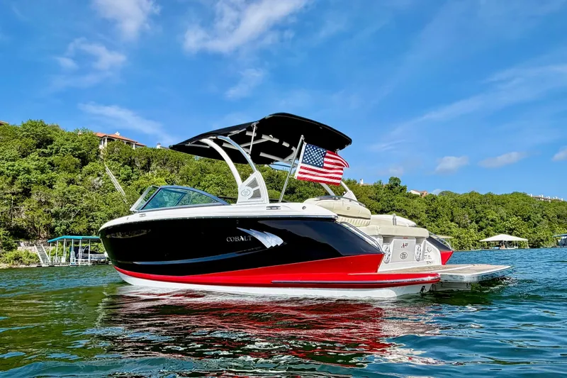 Slide: The Image of 2017 Cobalt A25 boat on water with American flag, lush greenery background. - 7