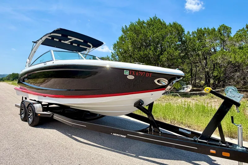 Slide: The Image of 2017 Cobalt A25 boat on trailer, parked on road with trees in background. - 21