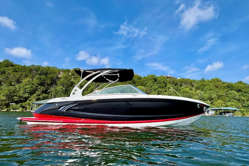 The Image of 2017 Cobalt A25 boat on a lake with lush green shoreline and blue sky. - 1