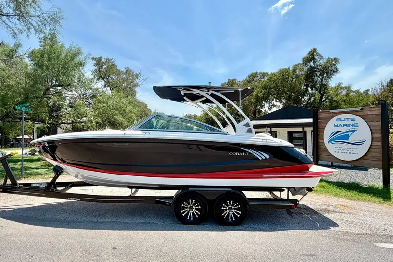 Slide: The Image of 2017 Cobalt A25 boat on trailer at Elite Marine dealership, sunny day. - 19