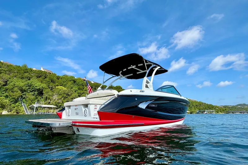 Slide: The Image of 2017 Cobalt A25 boat on water, blue sky, lush green shoreline in background. - 2