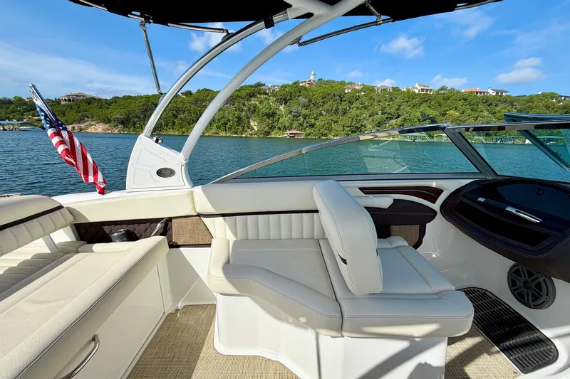 Slide: The Image of 2017 Cobalt A25 boat interior with American flag, lake view, and lush green shoreline. - 16