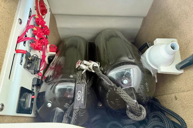 Slide: The Image of 2017 Cobalt A25 boat compartment with wiring, fenders, and a pump. - 37
