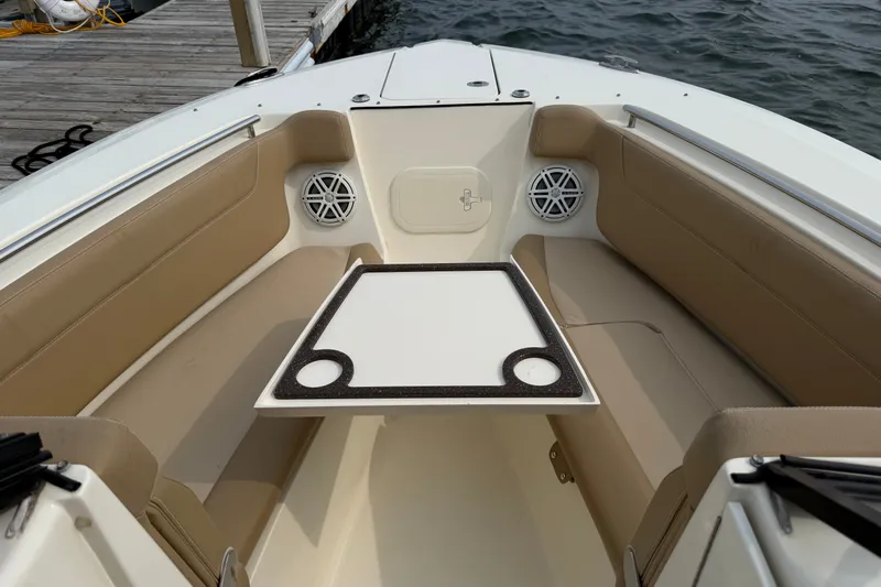Slide: The Image of 2018 Scout 275 Dorado boat interior with seating and table, docked by the water. - 11