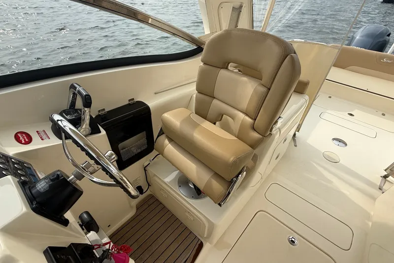 Slide: The Image of 2018 Scout 275 Dorado boat interior with steering wheel and beige captain's chair. - 17