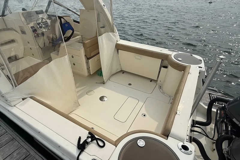 Slide: The Image of 2018 Scout 275 Dorado boat interior with seating and steering wheel, docked by the water. - 8