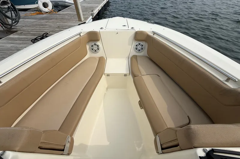 Slide: The Image of 2018 Scout 275 Dorado boat interior with tan seating and speakers, docked by the water. - 12