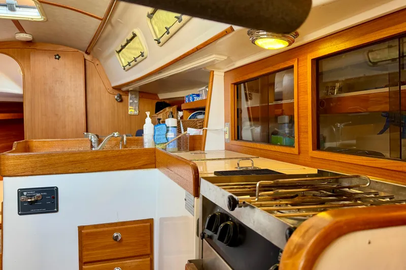 Slide: The Image of Interior of 2001 J Boats J/32 sailboat, featuring a compact kitchen with wooden cabinetry. - 19