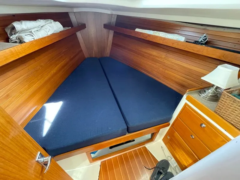 Slide: The Image of The cabin of a 2001 J/32 with wood paneling and blue cushions. - 29