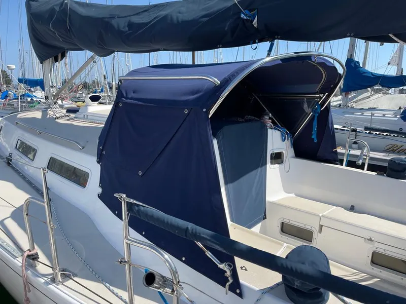 Slide: The Image of A 2001 J/32 sailboat with blue canvas cover docked at a marina. - 11