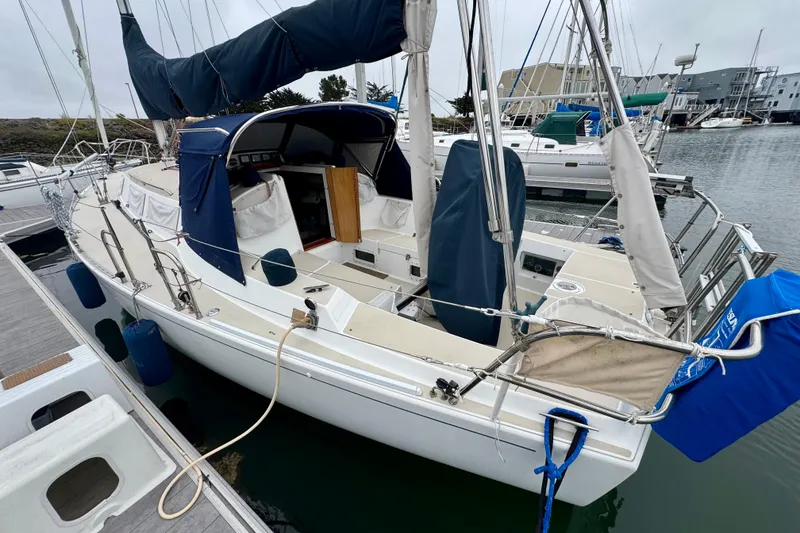 Slide: The Image of 2001 J Boats J/32 sailboat docked at marina, featuring blue covers and open cabin. - 12