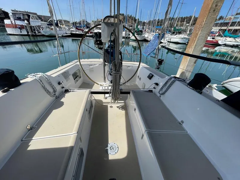 Slide: The Image of The cockpit of a 2001 J/32 with a steering wheel and benches, surrounded by boats in a marina. - 14