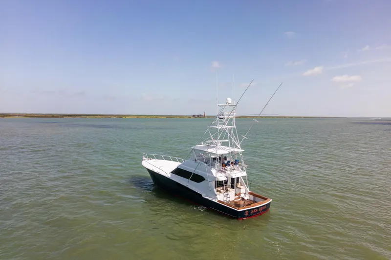 Slide: The Image of 2003 Hatteras 60 Convertible yacht on calm waters under clear skies. - 2
