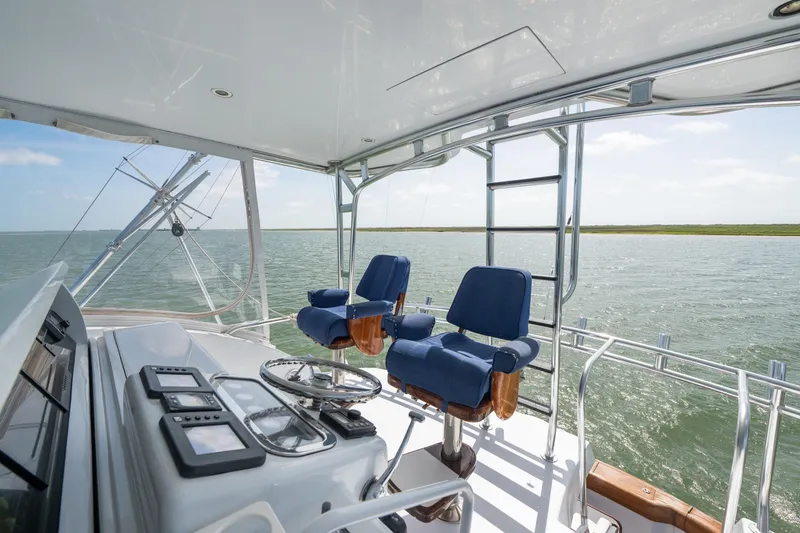 Slide: The Image of Helm of 2003 Hatteras 60 Convertible yacht with blue captain chairs and ocean view. - 7