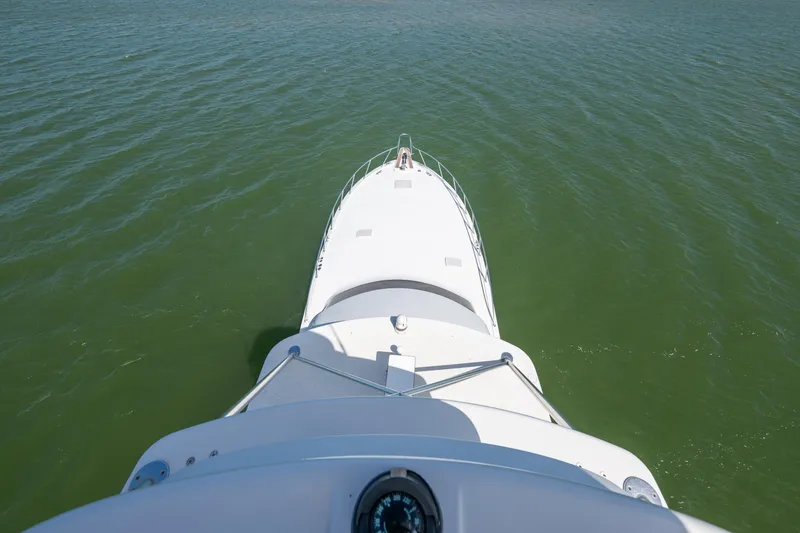 Slide: The Image of Bow view of 2003 Hatteras 60 Convertible yacht cruising on calm green waters. - 13