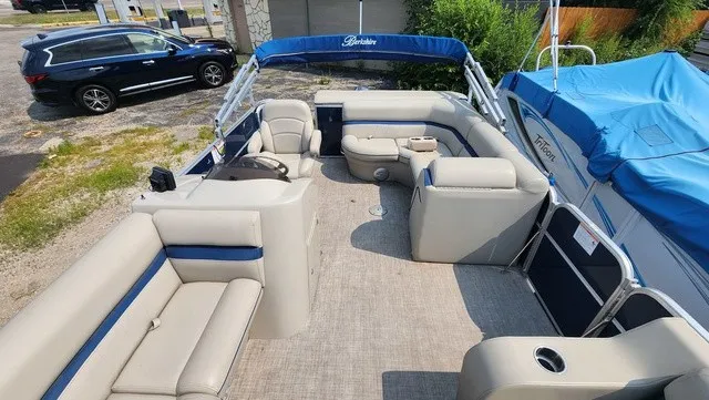 Slide: The Image of A 2017 Berkshire 17CL 2.0 pontoon boat with blue and beige seating, parked in a lot. - 8