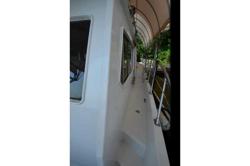 Slide: The Image of 1985 Kha Shing 40 yacht deck with canopy and railing, docked near lush greenery. - 18