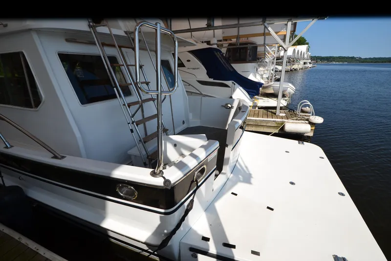 Slide: The Image of 1985 Kha Shing 40 yacht docked at a marina, featuring a spacious deck and ladder. - 8